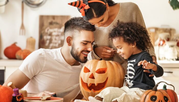 Family with young child decorating Halloween pumpkin